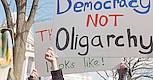 Demonstriender mt einem Schild "Democracy not Oligarchy." Protestierende mt einem Plakat "Democracy not Oligarchy."
